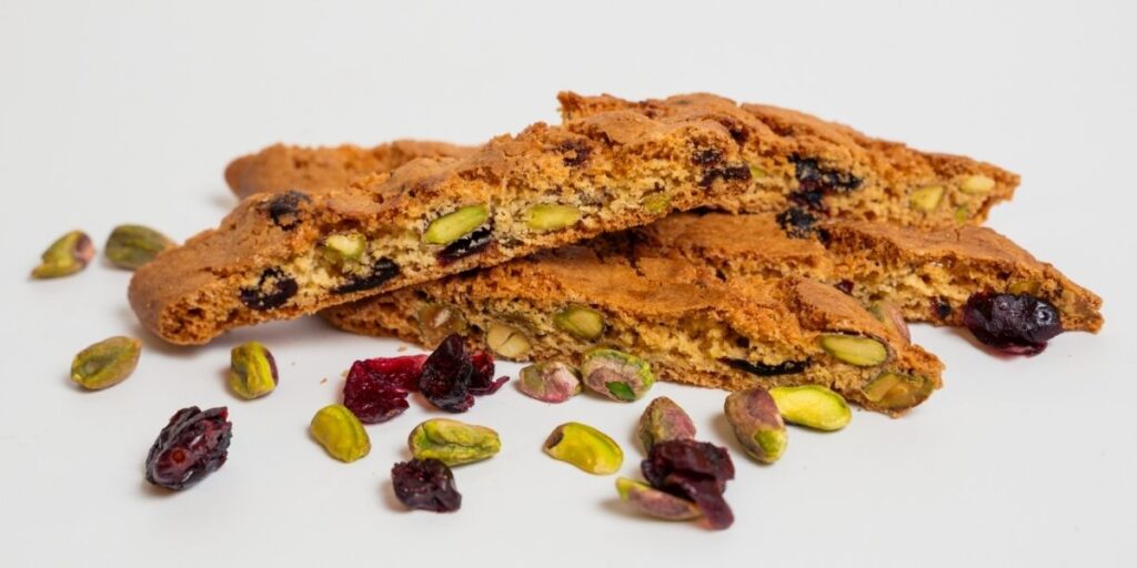 Cranberry pistachio biscotti slices with whole pistachios and dried cranberries on a white background