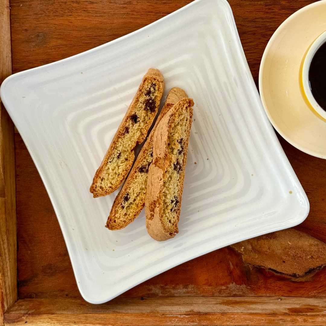Chocolate Biscottini with Belgian chocolate chunks on a plate next to a cup of coffee