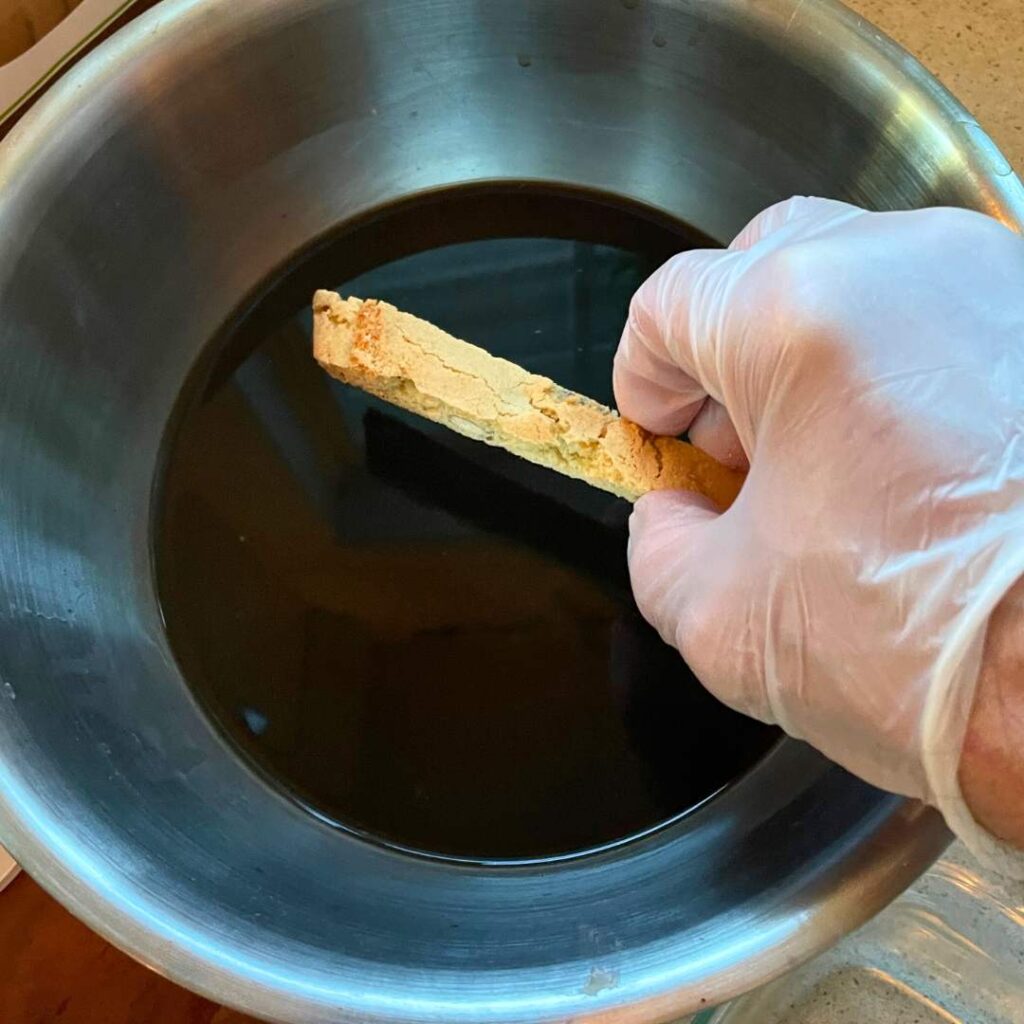 Hand dipping anise biscotti into espresso for tiramisu preparation
