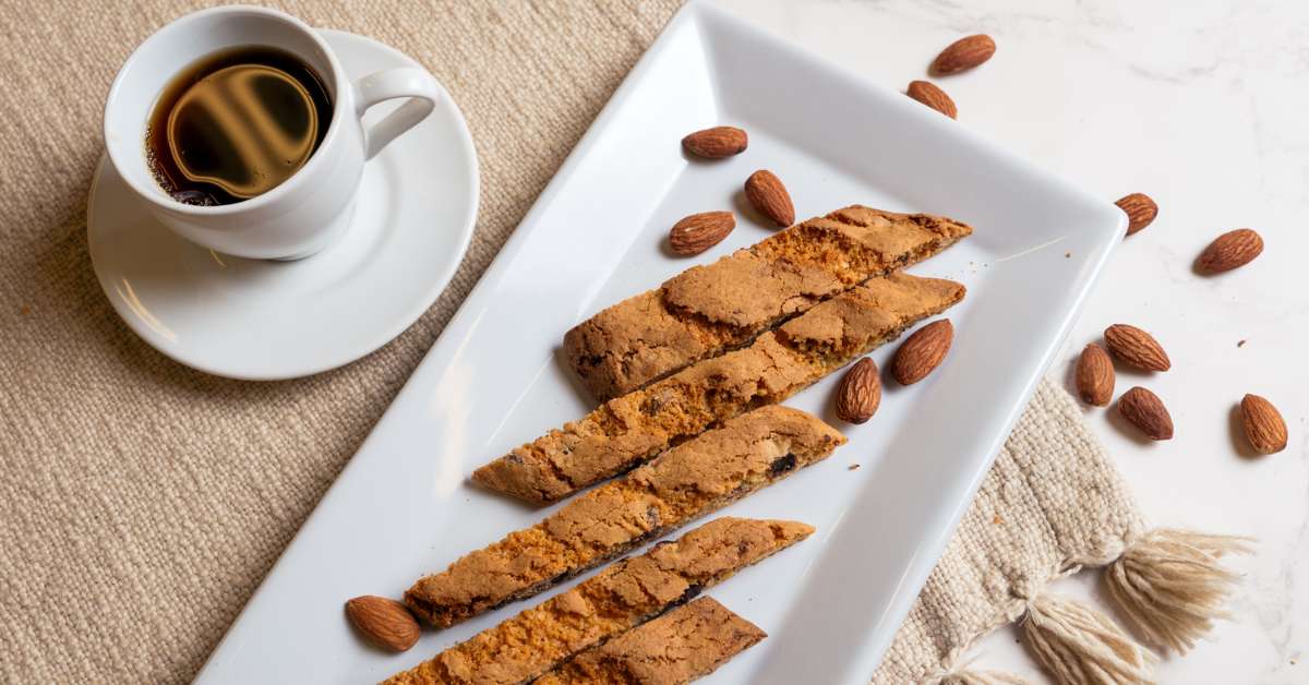 Almond Biscotti on a platter with espresso and almonds scattered on the mat
