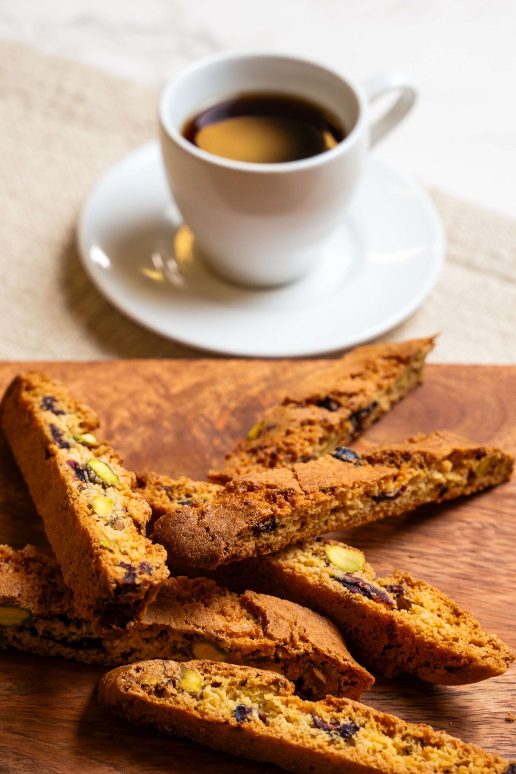 Plate of cranberry pistachio biscotti next to a cup of coffee