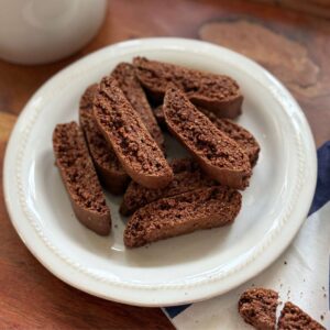Gluten Free Chocolate Anise Biscotti on a white plate beside a freshly brewed espresso