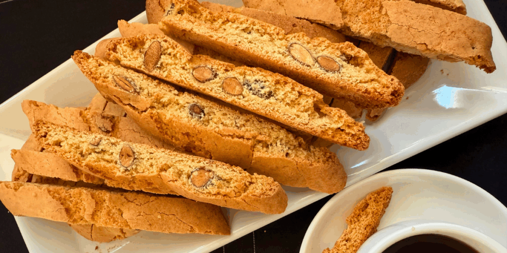 Almond biscotti on a plate next to a cup of coffee, hand-crafted small batch by The Biscotti Company