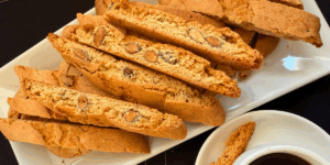 Almond biscotti on a plate next to a cup of coffee, hand-crafted small batch by The Biscotti Company