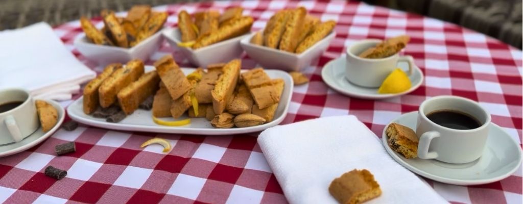 Table spread of biscotti with coffee cups and napkins that looks like the end of a party
