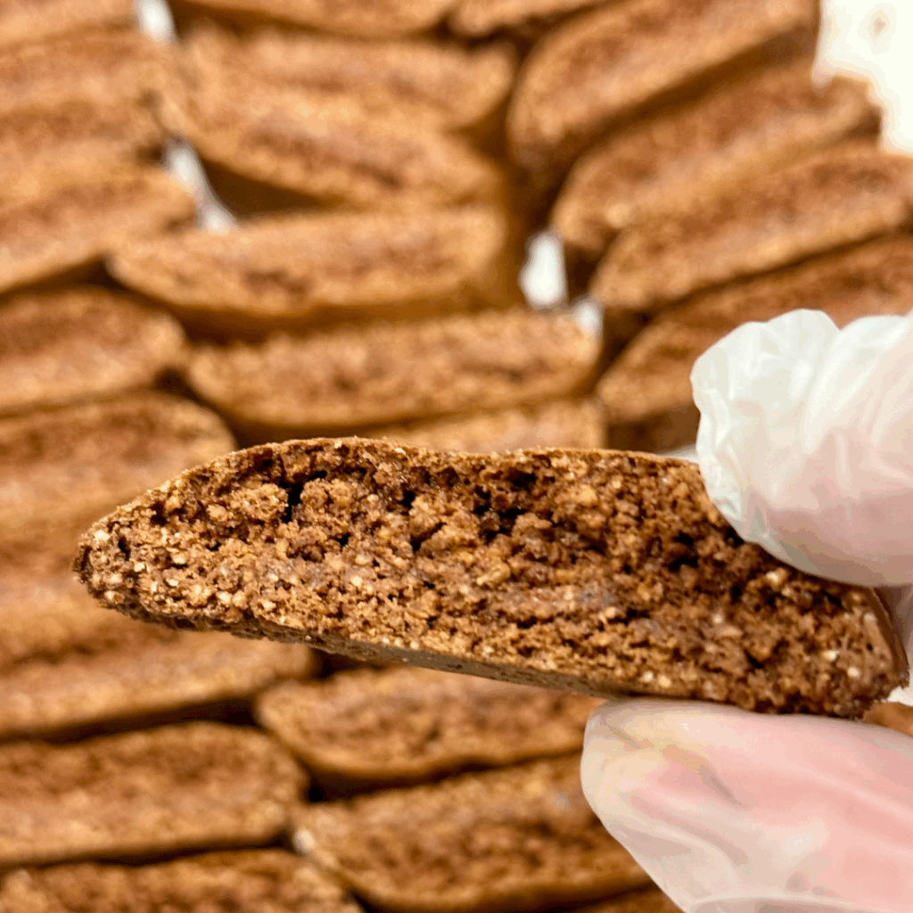 Hand dipping Chocolate Anise Biscottini into espresso, showing crisp texture and perfect dunk.