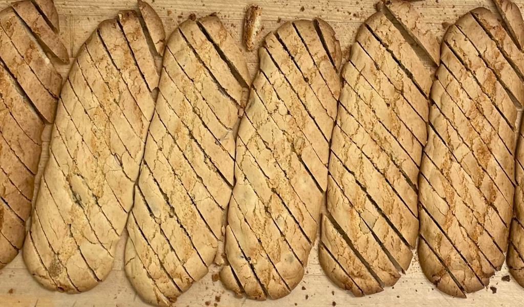 Rows of freshly baked biscotti loaves sliced on a butcher’s table before the second bake