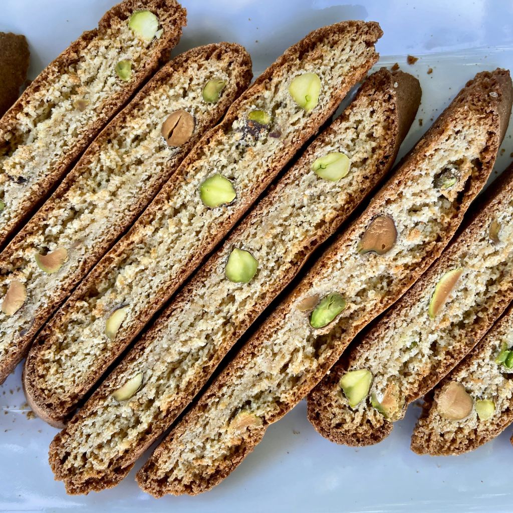 Gluten free chia pistachio biscotti with whole pistachios and chia seeds in a crisp golden slice.