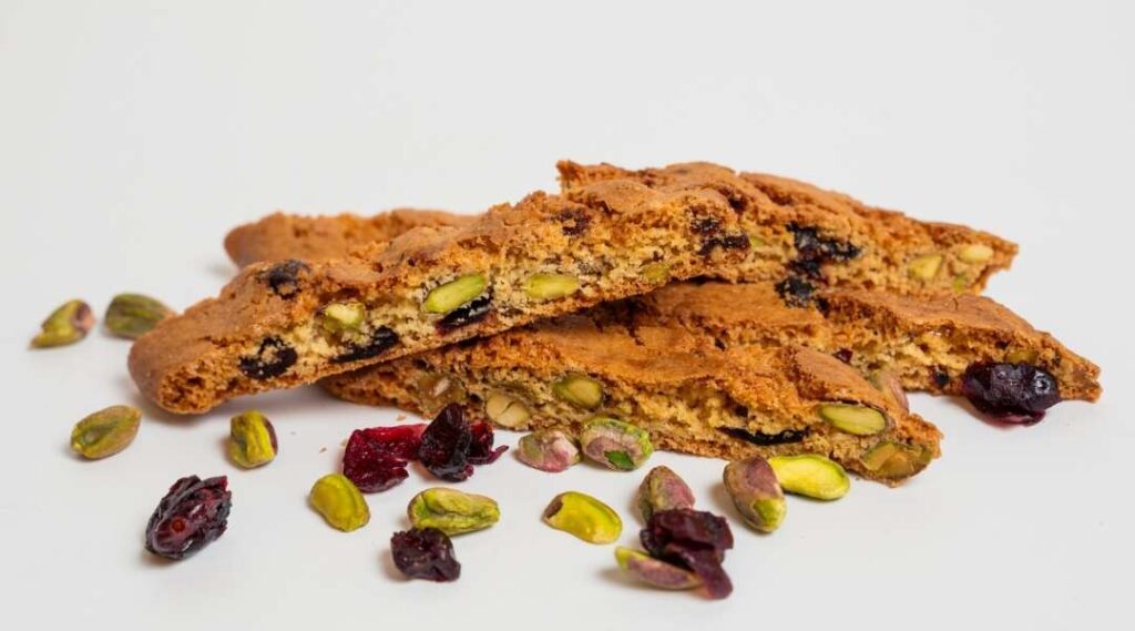 Cranberry Pistachio Biscotti on a counter with roasted pistachios and cranberries