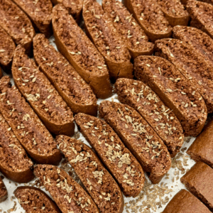 Close-up of Chocolate Anise Biscottini stacked on a plate showing crisp texture and dark cocoa color with anise seeds.