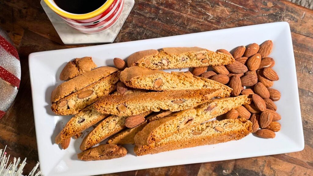 Plate of almond biscotti served with coffee in a festive setting, showing traditional Italian-style biscotti with a crisp texture