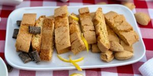 Closeup of Lemon Biscottini on a white plate with a fresh lemon wedge.