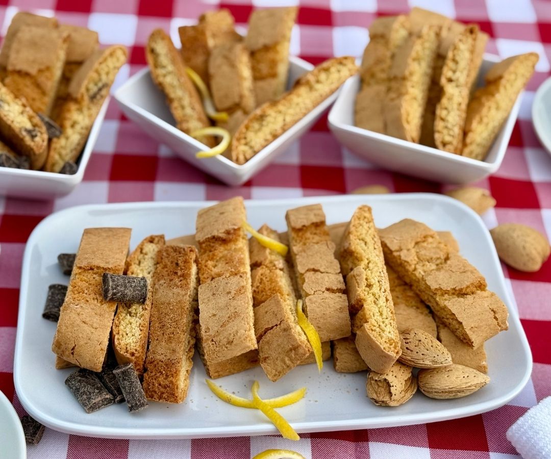 Assorted biscottini flavors on plates, including lemon, chocolate, and amaretto.