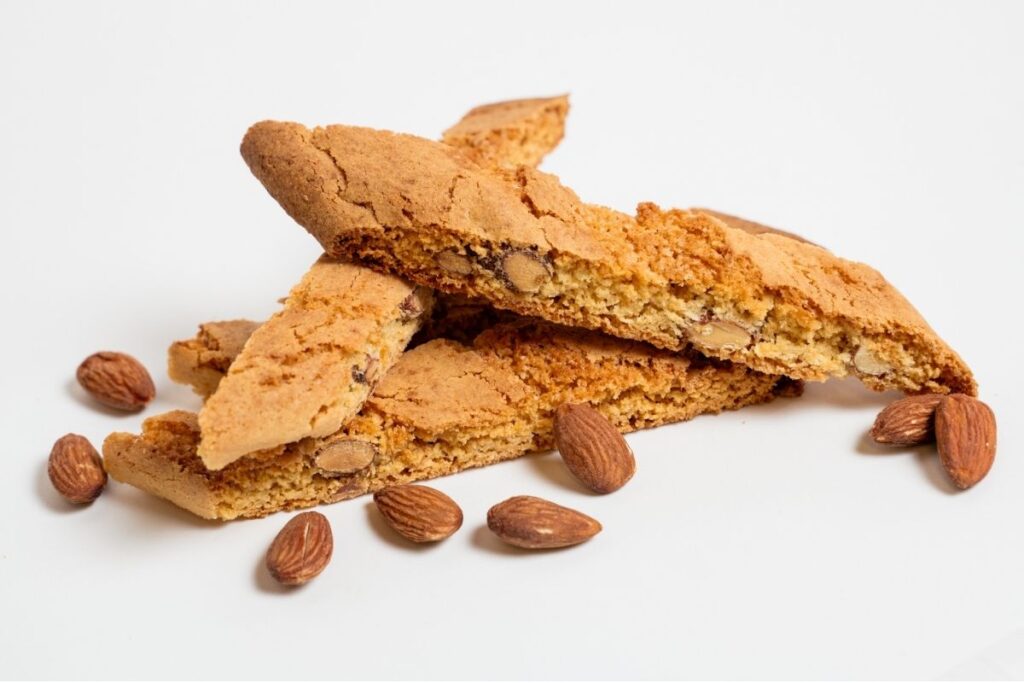 Stacked almond biscotti baked twice with whole almonds, showing a crisp texture on a white background