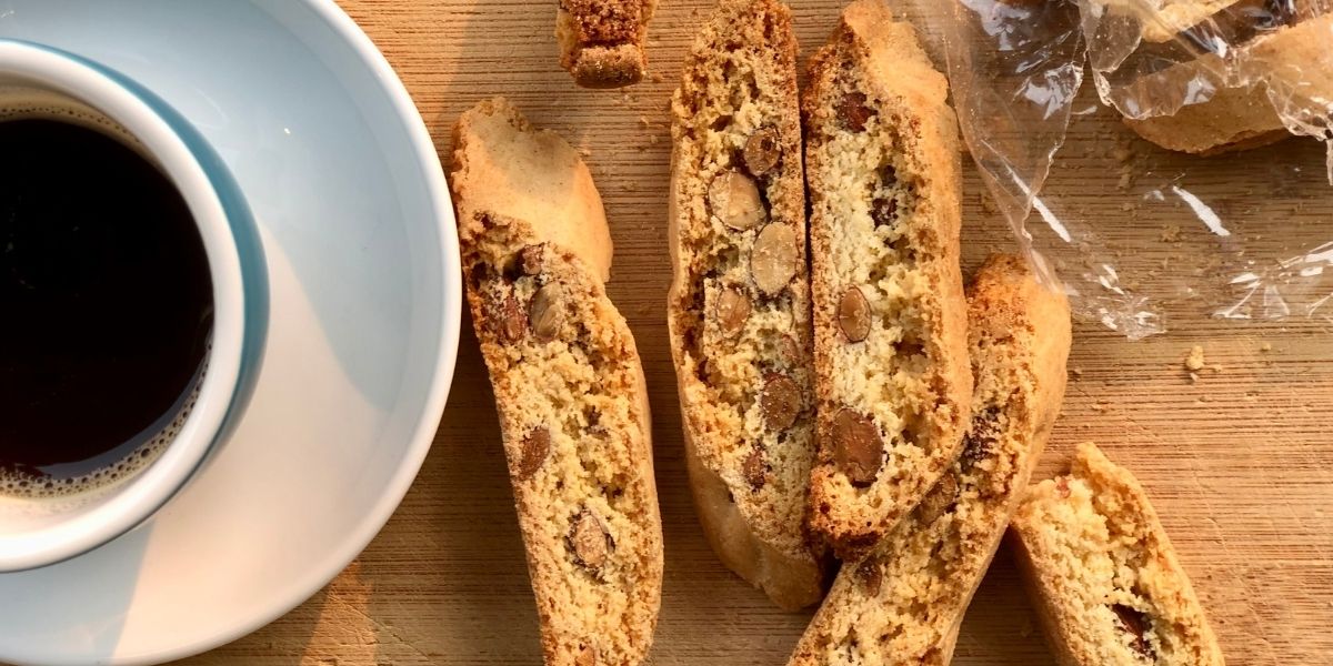 Handmade biscotti slices showing a crisp snap and crunchy texture on wooden board with coffee