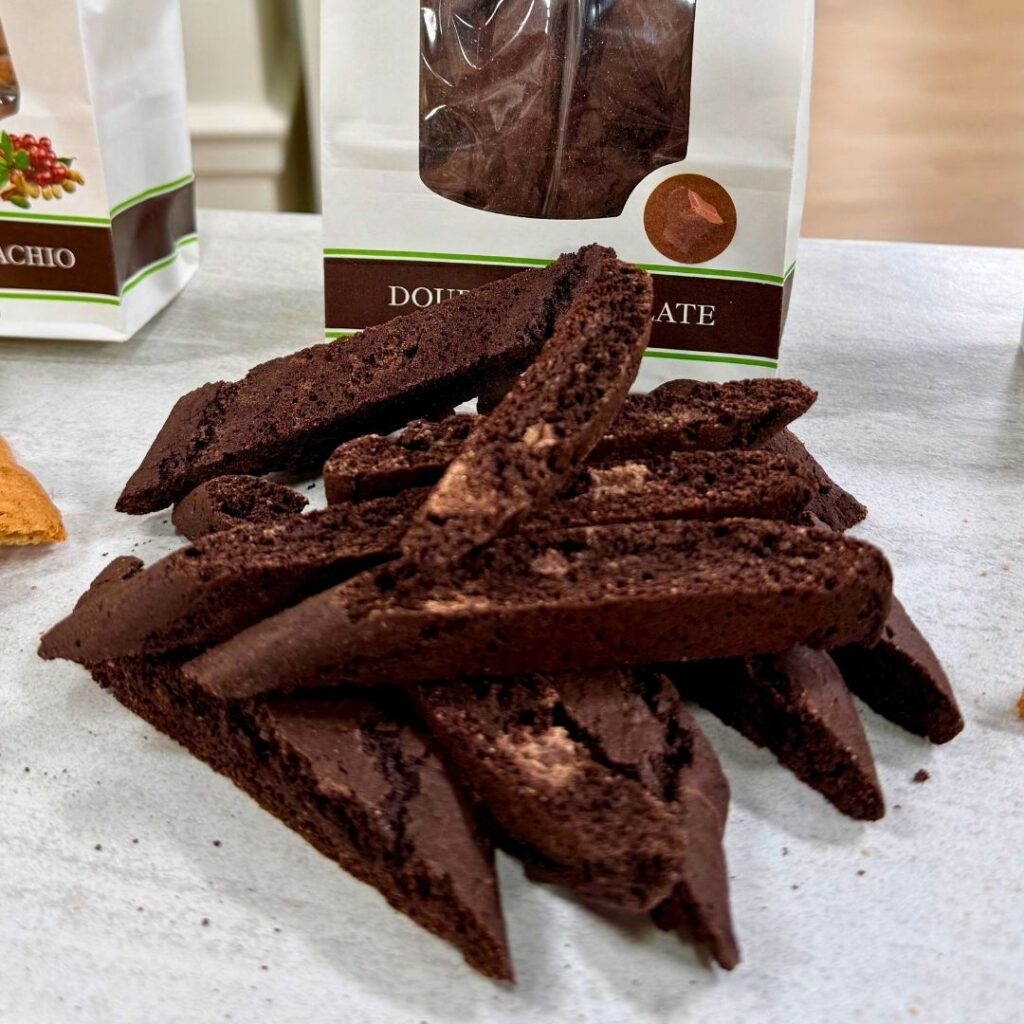 Stack of double chocolate biscotti cookies with The Biscotti Company bag in the background.