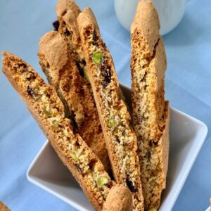 Cranberry pistachio biscotti close-up in a white bowl with whole pistachios