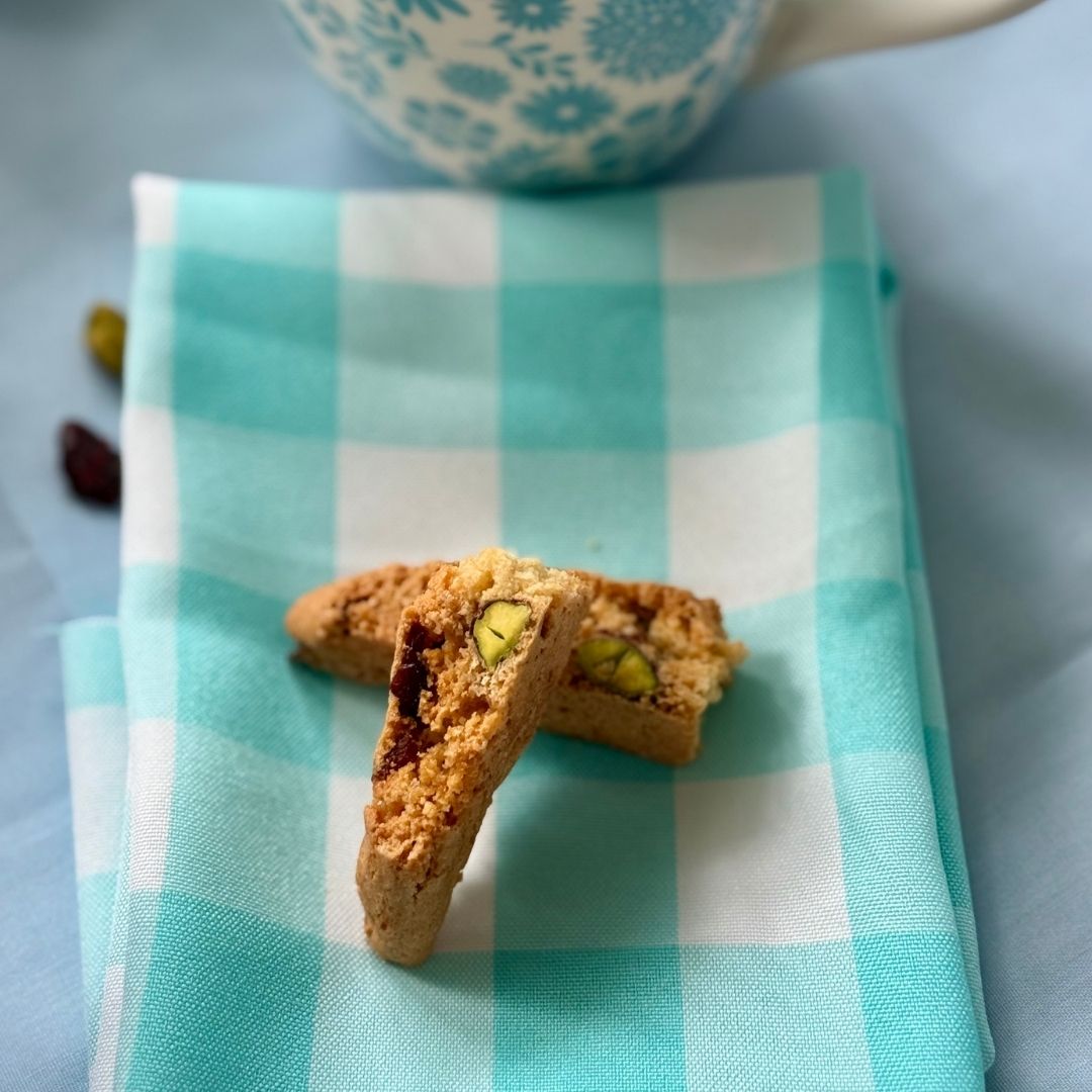Cranberry pistachio biscotti pieces on a teal checkered napkin