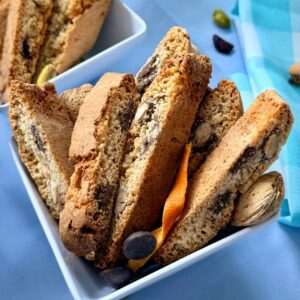 Dark chocolate and orange almond biscotti close-up in a white bowl with orange peel