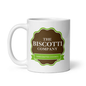 White ceramic mug showing a brown logo plaque with green border reading 'THE BISCOTTI COMPANY' and a green ribbon 'HANDCRAFTED COOKIES'