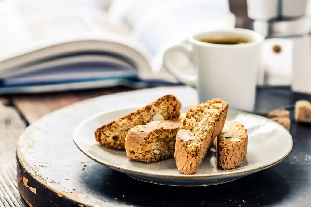 Biscotti slices on a plate with a white mug of coffee in the background